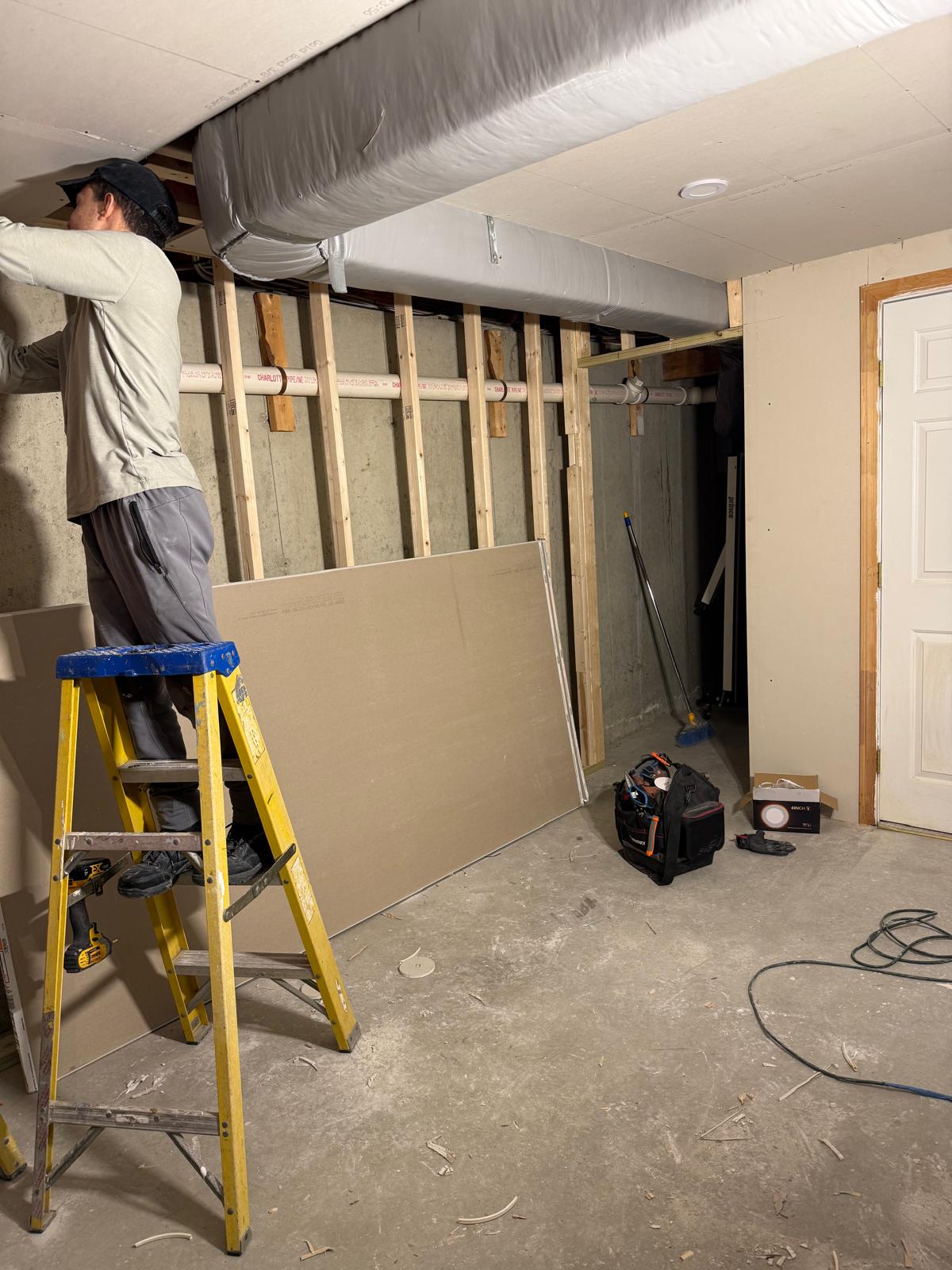 Drywall being installed on a basement ceiling