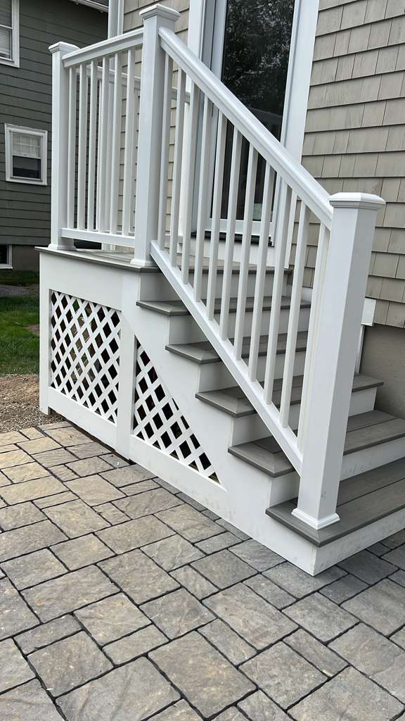 Finished exterior entry stairs with white railing and lattice skirting