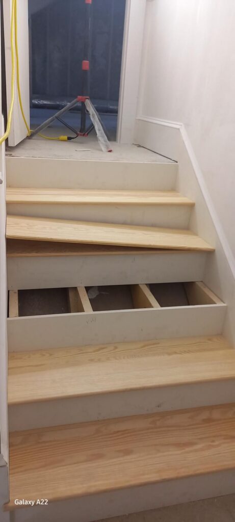 New pine stair treads being installed on an interior staircase