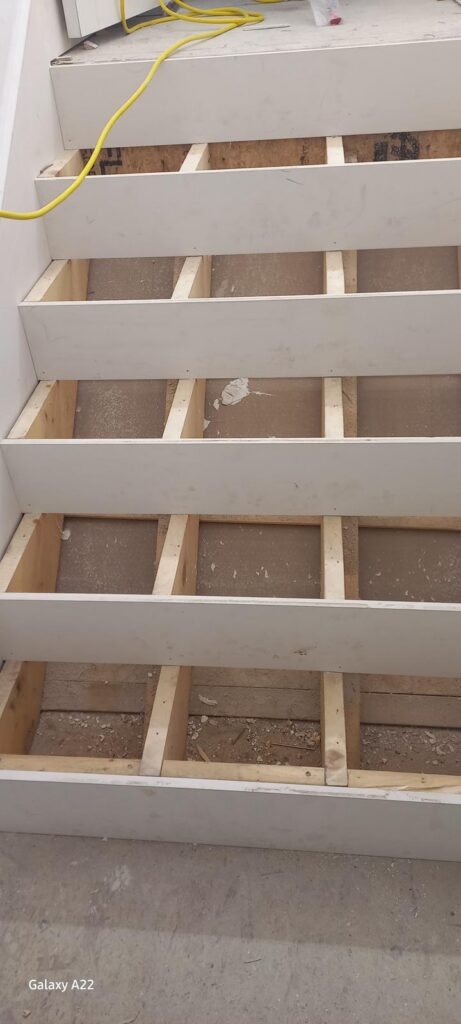 Staircase with old treads removed and framing exposed during renovation