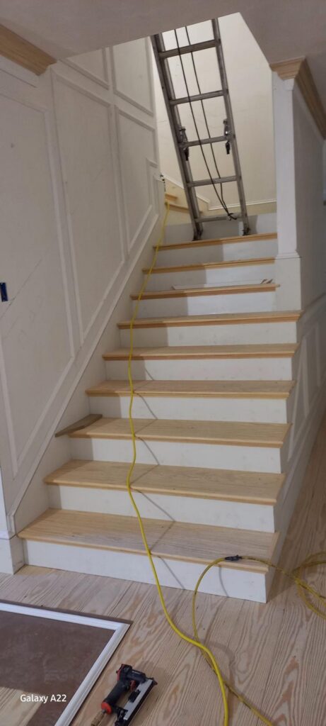 Renovated interior staircase with new treads, white risers and wall paneling