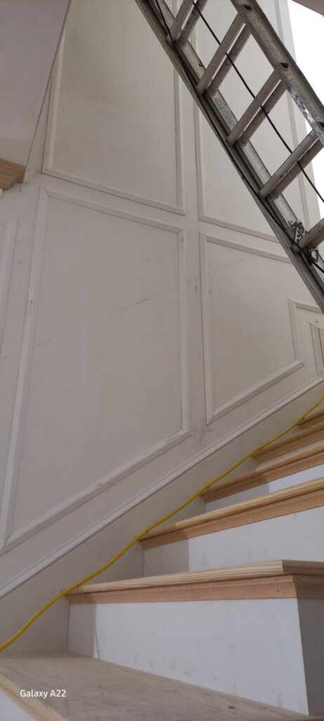 Picture-frame wall paneling along a staircase by Boldwood Finishes